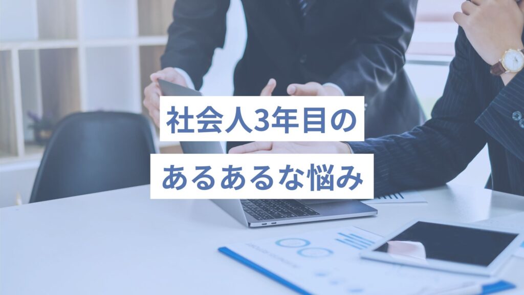 スーツの男性二人が、デスクに資料を広げながら１台のノートパソコンを一緒にみて指さしながら何かを話し合っている様子