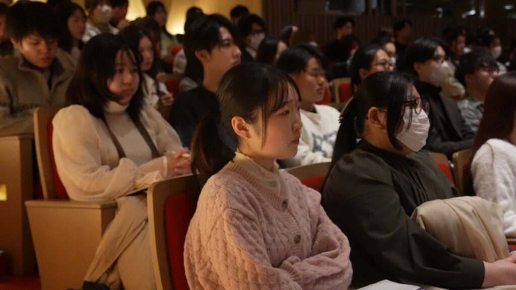 コンベンションのスピーチを真剣に聞く参加者たち